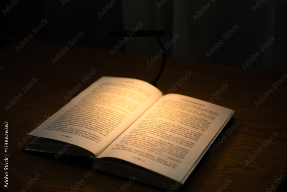 Fototapeta premium A convenient clip-on reading lamp with color options, placed over a book on the table for reading