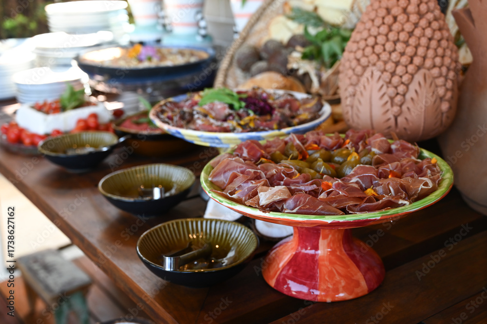 Obraz premium gourmet charcuterie platter close up, prosciutto ham and pickled vegetables antipasto, luxurious fine dining buffet setup, decorated table centerpiece and food