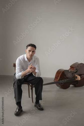 young man sitting on chair near contrabass