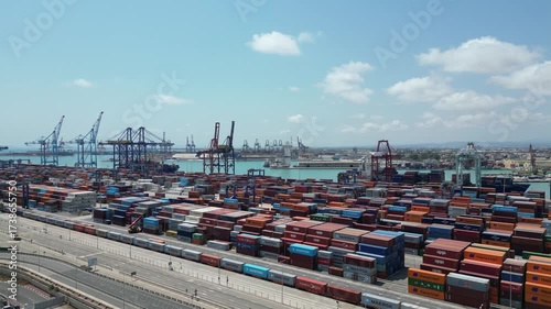 Aerial drone view of Valencia commercial port with shipping containers, cranes, and cargo ships