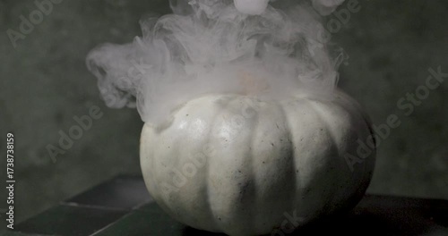 white pumpkin on mystic dark green smoky background, halloween theme, selective focus
