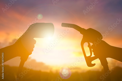 Electric Vehicle Charging Plug and Fuel Pump Nozzle Comparison at Sunset