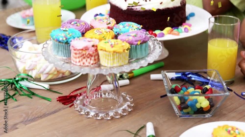 Camera opening focusing on cupcakes while confetti drifting then revealing tiered celebratory cake