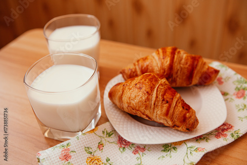 Two croissants and glasses of milk  on the table on the kitchen