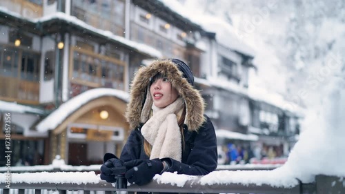 Happy Asian woman using digital camera taking selfie or vlogging while travel Ginzan onsen hot spring ryokan in Yamagata, Japan in snow day. Attractive girl travel local village on winter vacation.