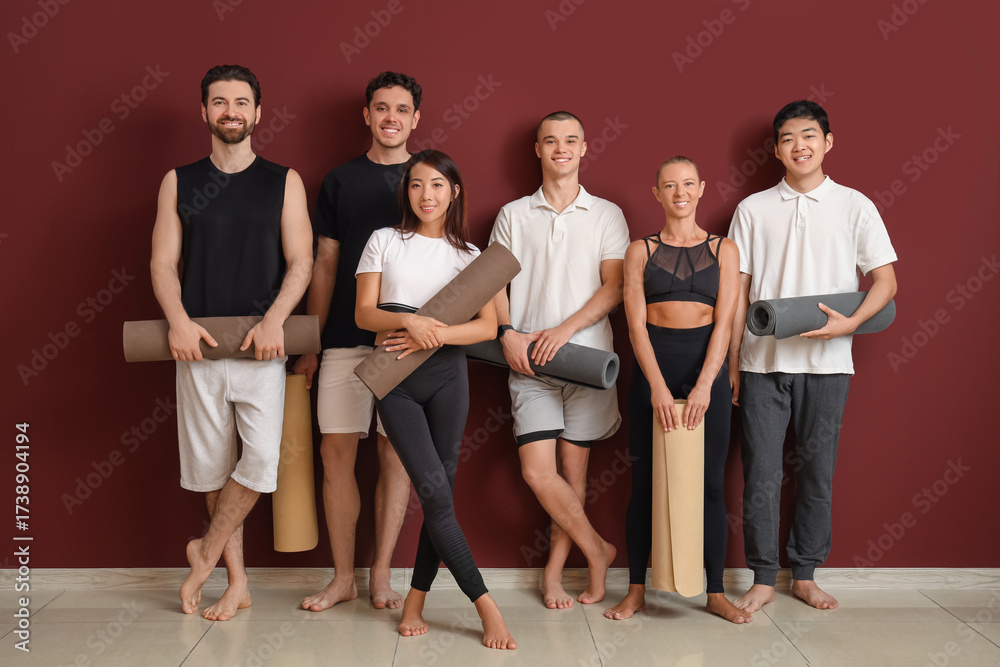 Obraz premium Diverse group of smiling young adults holding yoga mats, wellness and fitness lifestyle, studio workout session