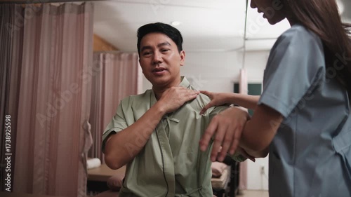 Male Asian patient is hand stretching, treated for health recovery for muscle pain relief by female physical therapist doctor, passive medical therapy at spa clinic, and wellness massaging healthcare.