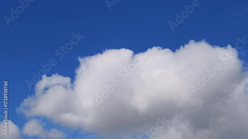 A stunning time-lapse capturing the dynamic movement of fluffy white clouds racing across a vibrant blue daytime sky. Perfect for background footage, meditation videos, weather content, or projects ne