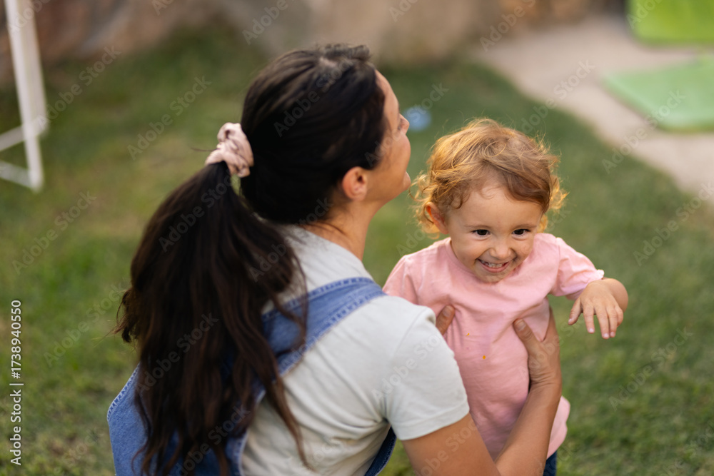 Fototapeta premium Young woman and her cheerful child enjoying time outdoors together on a sunny day