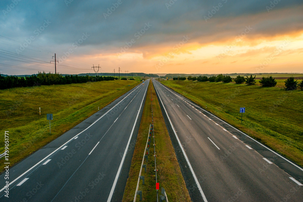 Fototapeta premium a colorful yellow sunrise over an empty highway in Belarus