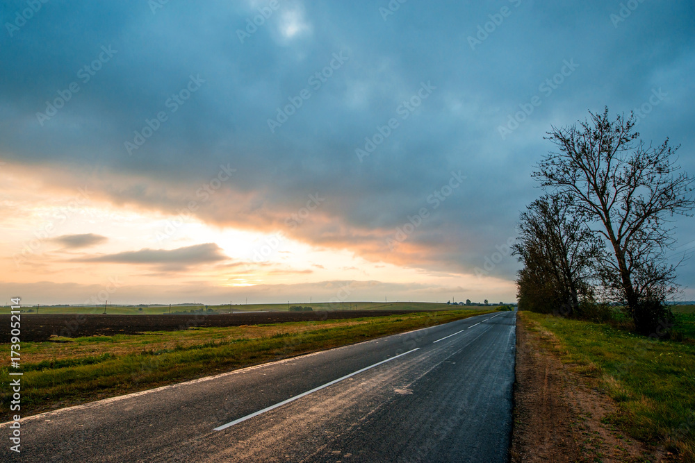 Fototapeta premium a colorful yellow sunrise over an empty highway in Belarus