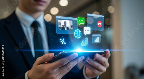 Wallpaper Mural A businessman in a suit holds a smartphone displaying holographic communication and data icons, representing modern digital interaction and business technology. Torontodigital.ca