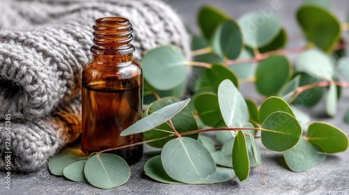 Eucalyptus Leaves with Amber Essential Oil Bottle on Soft Gray Surface