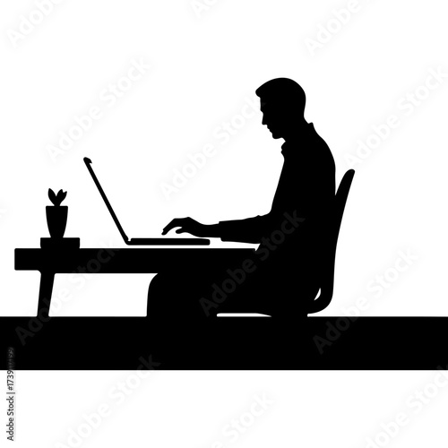 Silhouette of a man working on a laptop at a desk