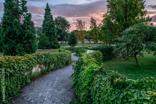 Curved pathway through Yamaguchi park garden with trimmed hedges at sunset in Pamplona, Navarre, Spain, showing peaceful zen design