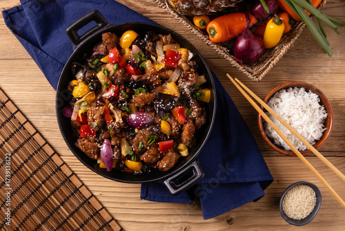 Traditional Asian sweet and sour pork with paprika and sesame. Prepared in a wok.
