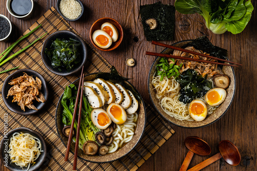 Traditional ramen with jerked pork or chicken.  With udon or ramen noodles. Served in classic bowls. Gyoza dumplings and mushrooms in the background.