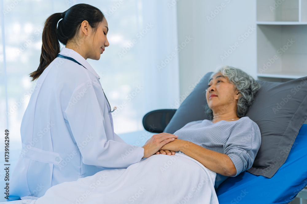 Fototapeta premium Doctor is examining elderly female patient in ward while doctor is checking her condition in recovery room. Medical and healthcare concept.