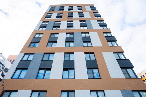 The modern façade of this multi-story building features warm tones with contrasting gray accents. Rectilinear shapes and large windows create a feeling of spaciousness and light.