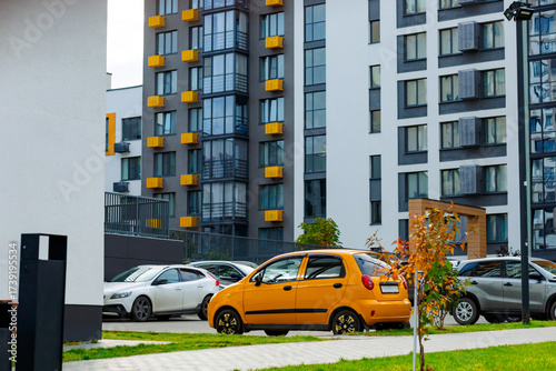 Vászonkép A bright yellow car is parked near a modern residential complex