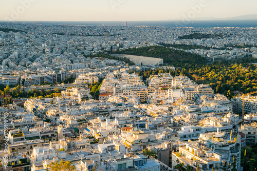 Panoramic view of Athens, Greece from the top of Lycabettus Hill at sunset. The Acropolis can be seen in the distance with the urban sprawl of the Greek capital spreading toward the horizon. White
