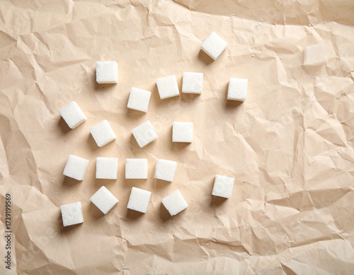 Delicate white sugar cubes thoughtfully arranged on a richly textured brown paper, their pristine form contrasting beautifully with the rustic surface, hinting at purity and sweetness