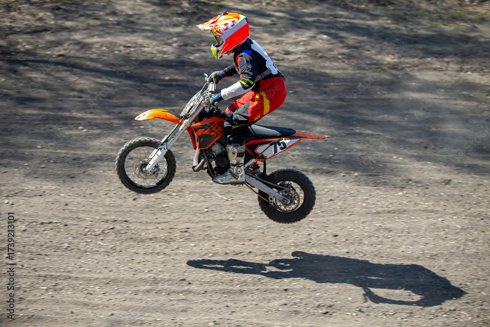Obraz premium Child motocross rider performing jump on dusty track