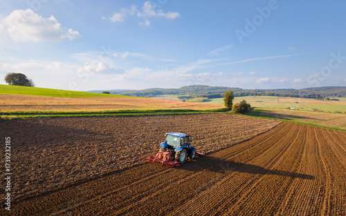 An aerial photograph of a tractor plowing a field in the picturesque countryside.
