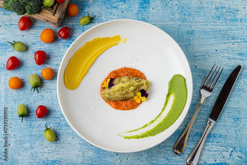 Eggplant puree with colorful sauces and edible flower garnish