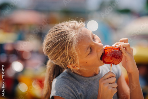 Bilde på lerret Girl enjoying a candied apple at the amusement park