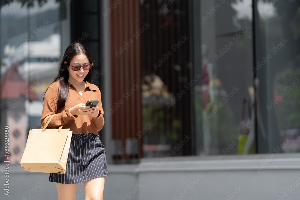 Fototapeta premium Young asian woman shopping, navigating smartphone with smile