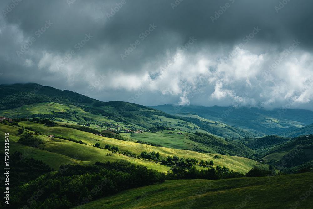 Fototapeta premium Rolling green hills with dramatic clouds, spring renewal mood, cinematic perspective