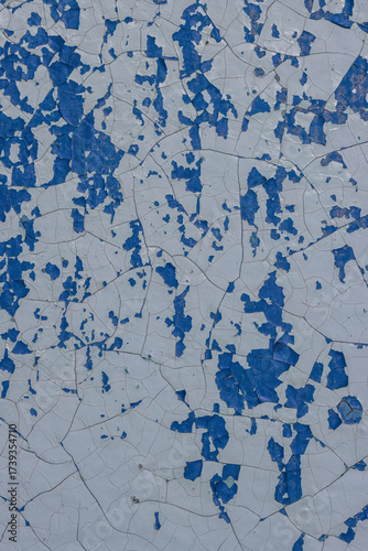 Blue peeling paint on the wall. Old concrete wall with cracked flaking paint. Weathered rough painted surface with patterns of cracks and peeling. High resolution texture for background and design.