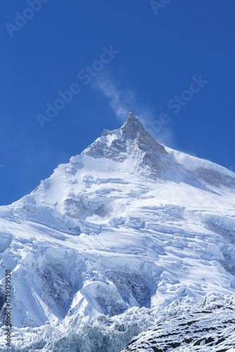 Wind whips snow off a majestic icy peak