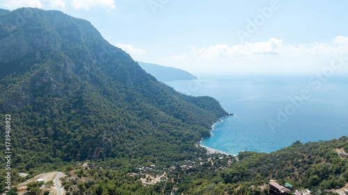 фотографія Coastal Serenity: A panoramic view unfolds, revealing a harmonious blend of nature's elements - lush mountains, expansive coastline, and crystal-clear turquoise waters under a vast azure sky