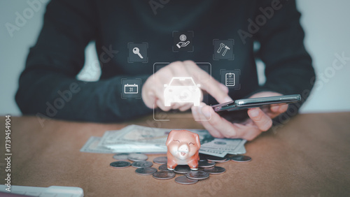 A person is using a mobile phone to manage car finances with a piggy bank and money on the table. Managing vehicle expenses, finance, insurance. Concept mobile app advertising, and maintenance.