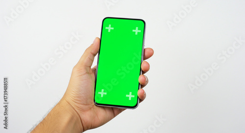Confident hand holding modern smartphone with vibrant green screen for creative editing and content integration