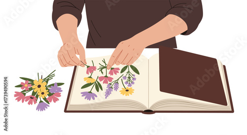 Hands arranging pressed flowers in an open book.