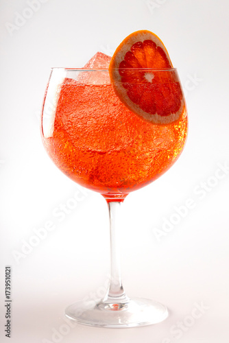 Glass of pink gin and tonic with a slice of grapefruit on a white background.