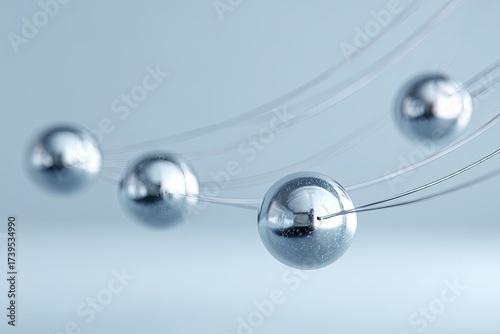 Close-up of shiny silver spheres suspended by nearly invisible curved strings against a blurred background