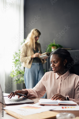Businesswomen collaborating on project at modern office