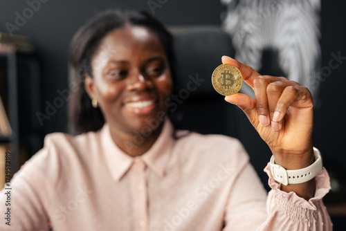 Happy black woman holding golden bitcoin coin