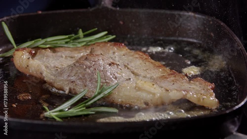 Fried Beef Steak Sizzling in Cast Iron Pan with Oil and Seasoning