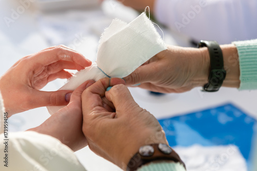 Two people's hands are bandaged with a piece of cloth. The action of working with the material.