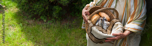 Φωτογραφία Man holding a basket with fish and bread
