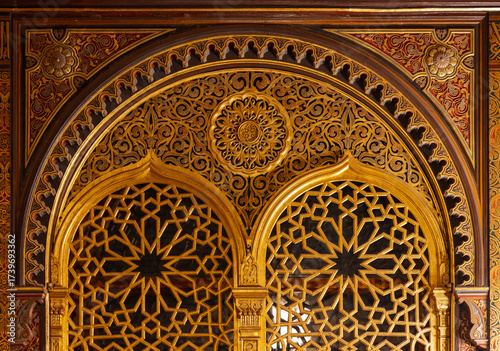 Golden archway featuring geometric lattice panels, ornate arabesque motifs