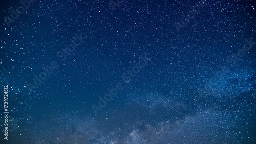A breathtaking view of a deep blue, star-studded night sky with soft, ethereal clouds drifting by