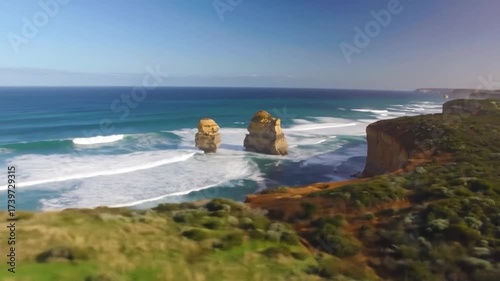 Aerial view of majestic sea stacks along a rugged coastline under a clear blue sky on a sunny day
