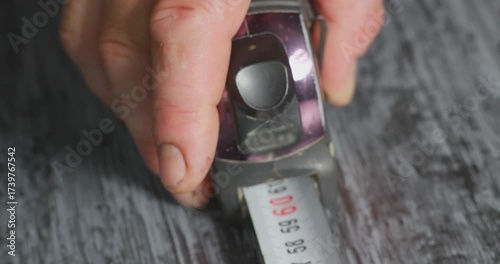 Worker using measuring tape on wooden surface