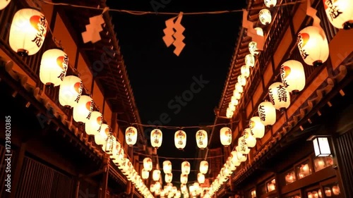 Illuminated alleyway at night, lined with traditional paper lanterns hanging from buildings with dark wood structures, creating a warm, inviting atmosphere